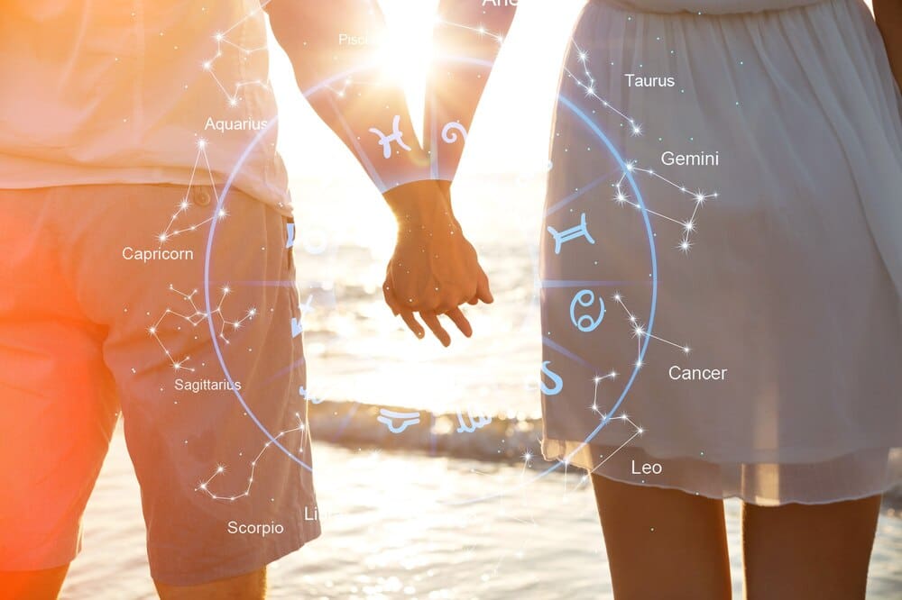 Hands of a couple with zodiac signs overlaid, symbolizing love compatibility.