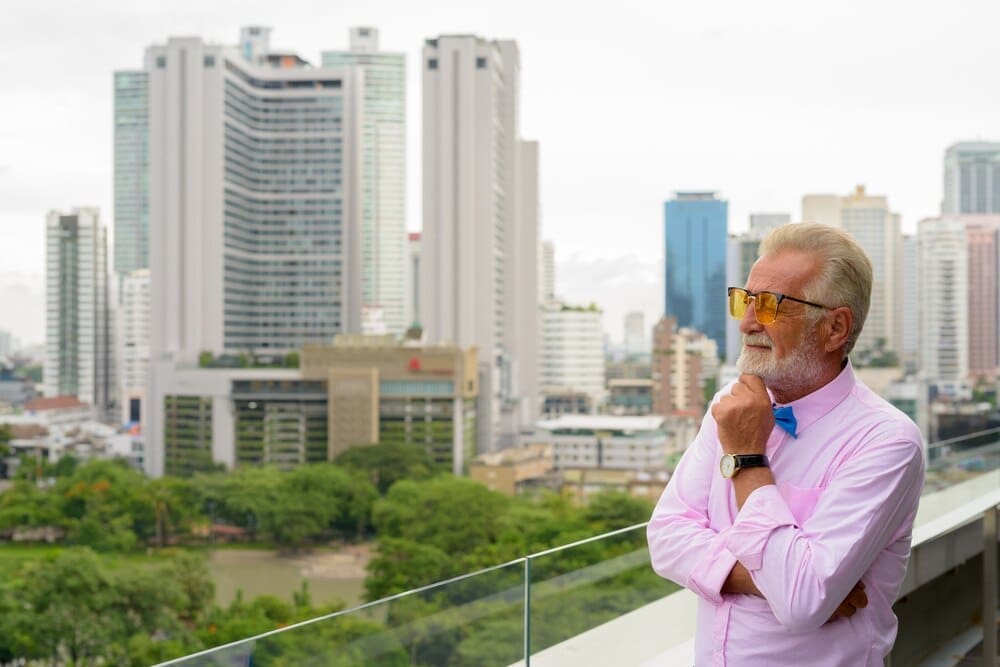 A senior man with a beard explores a city street in Bangkok, Thailand.