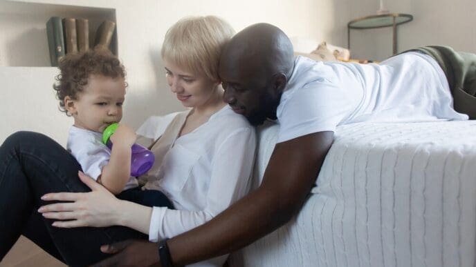 A multinational family smiles while spending time with a child.