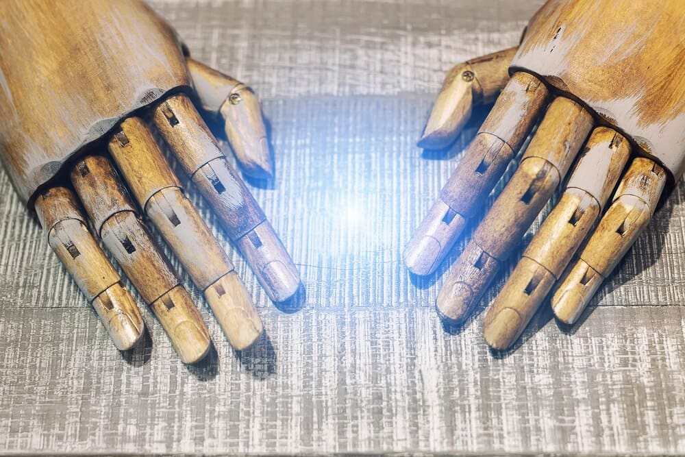 High-angle shot shows a pair of robotic hands resting on a wooden table.