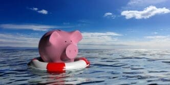 A red life buoy rests next to a white piggy bank on a blue sea, rendered in 3D.