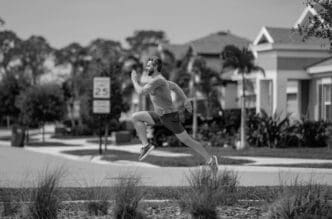 A man in sportswear runs on a street in a neighborhood.