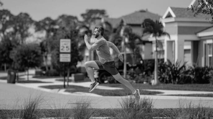 A man in sportswear runs on a street in a neighborhood.