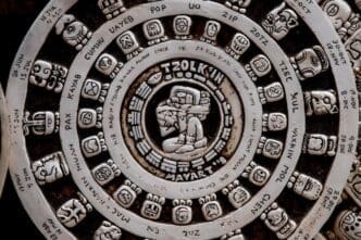 A large, circular stone carving features intricate Aztec symbols and glyphs, representing the Mesoamerican calendar.