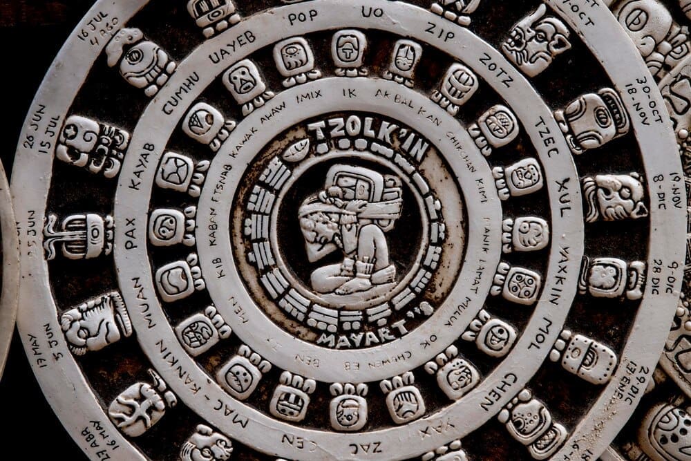 A large, circular stone carving features intricate Aztec symbols and glyphs, representing the Mesoamerican calendar.