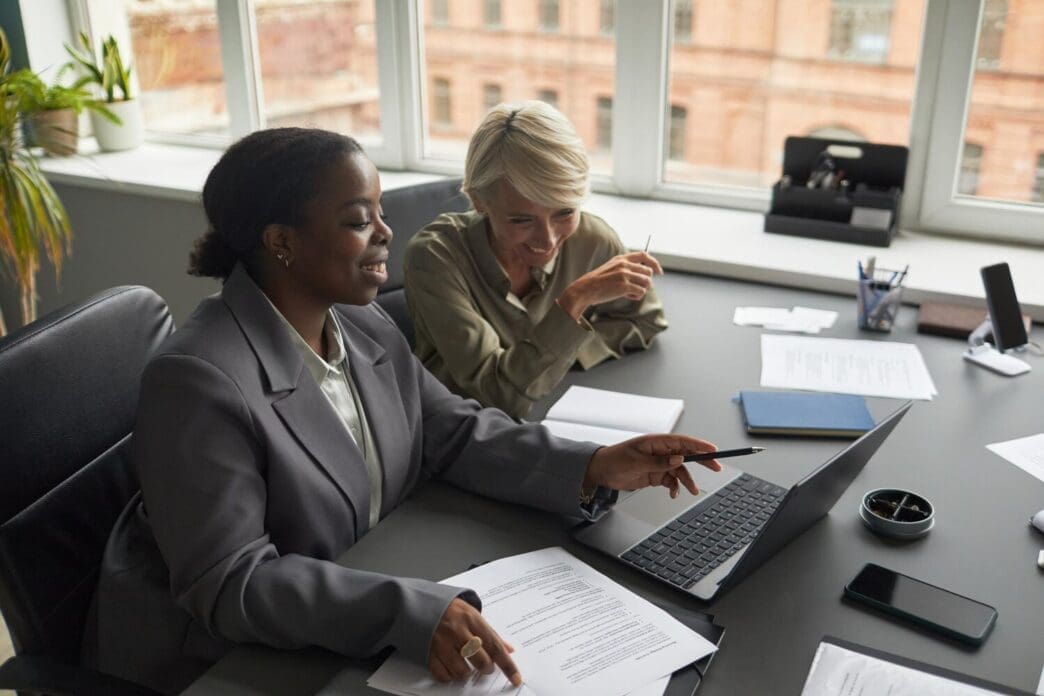 A middle-aged white woman and a young Black woman are working together, likely at a job.