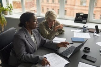 A middle-aged white woman and a young Black woman are working together, likely at a job.