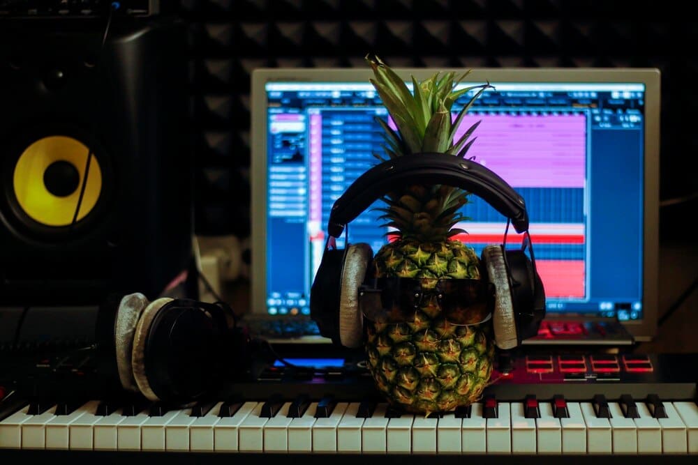 A pineapple wearing headphones appears to be producing music.