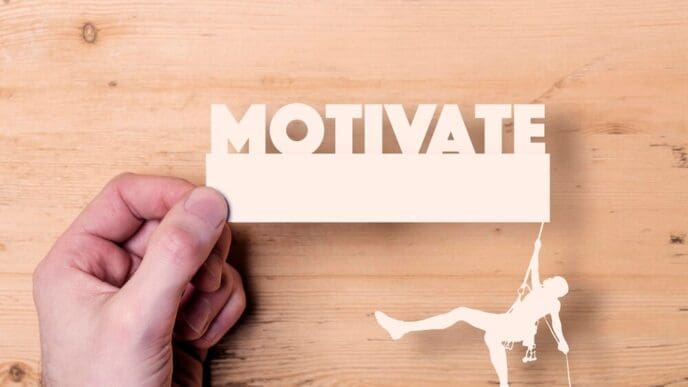A paper cutout shows a climber reaching for the word "motivate," representing a business concept.