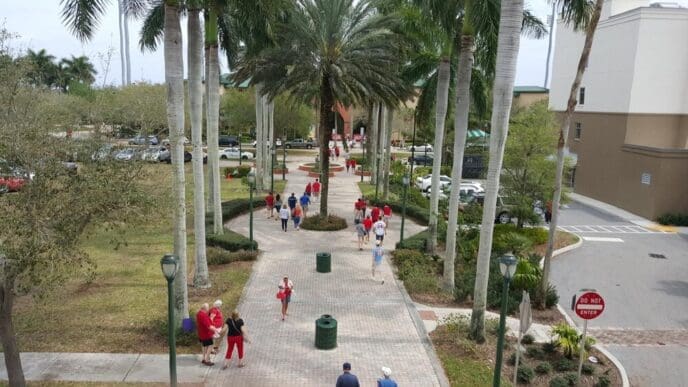People stroll along a street lined with palm trees.