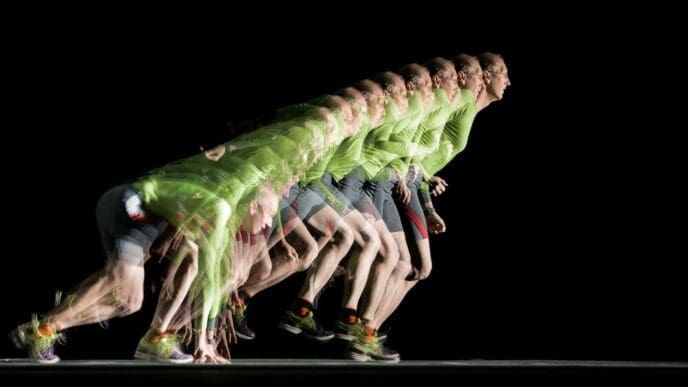 A runner is captured in a long exposure photograph with a stroboscopic effect, showing their motion through multiple flashes.