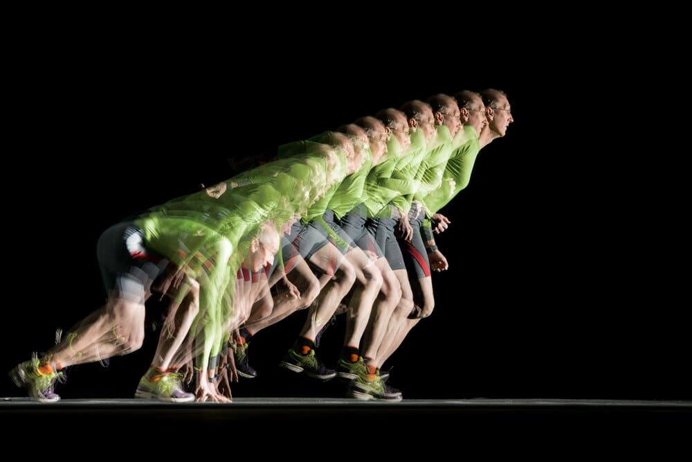 A runner is captured in a long exposure photograph with a stroboscopic effect, showing their motion through multiple flashes.