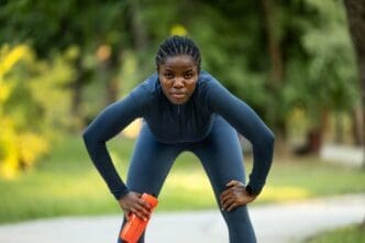 A Black woman in athletic wear stands in a ready position, poised for a run.