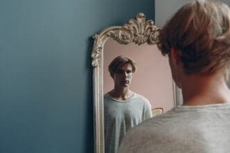 Portrait of a young European man looking at a mirror in an indoor studio setting.