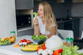 A smiling woman sits at a table, enjoying a healthy meal.