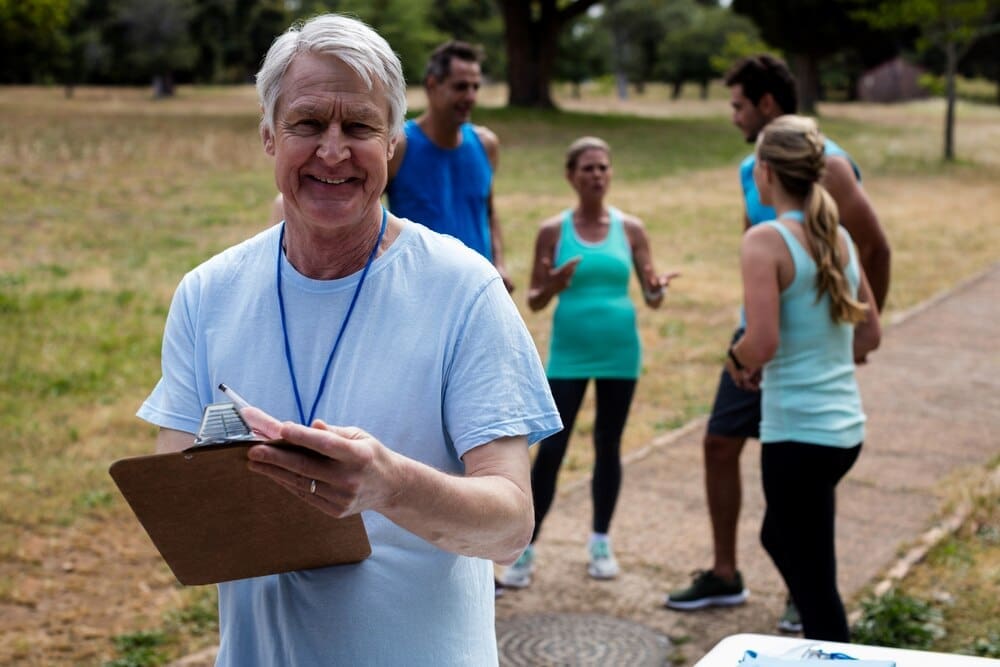A man smiles while holding a clipboard.