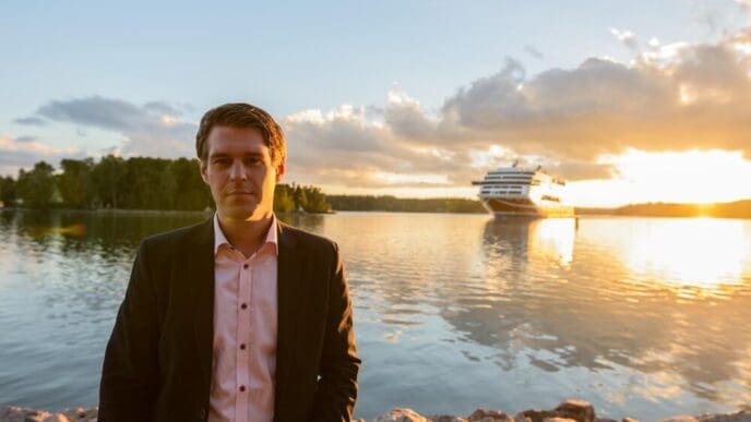 A young man stands in a lake, silhouetted against the sky.