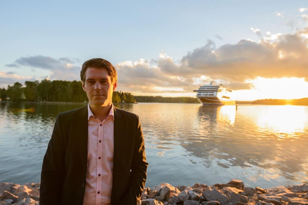 A young man stands in a lake, silhouetted against the sky.