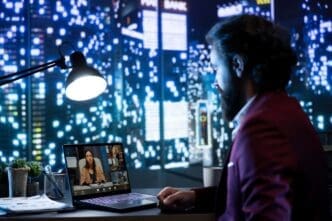 A person wearing a suit and tie speaks to a group of people on a computer screen during a video conference.