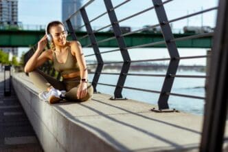 A young woman with earphones takes a break after running in an urban area.