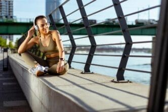 A young woman with earphones takes a break after running in an urban area.