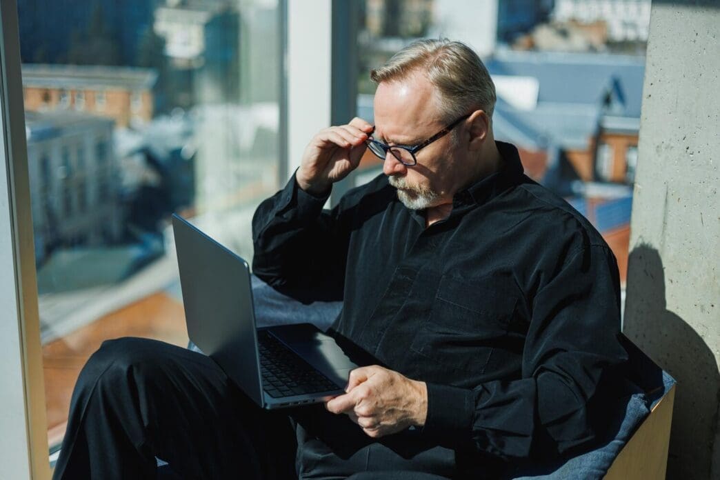 A man in a professional setting types on a laptop in a contemporary office.