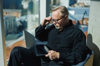 A man in a professional setting types on a laptop in a contemporary office.