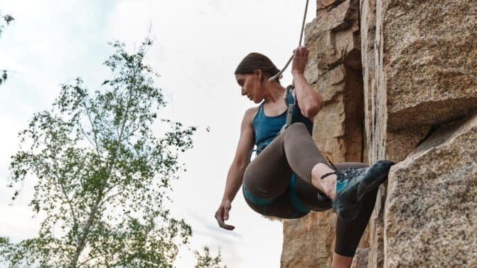 Close-up of professional women's rock climbing, showing hands gripping the rock face.