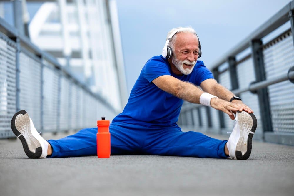 A senior man stretches his legs and warms up before a running workout.