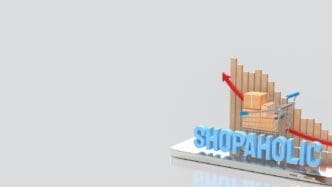 A 3D rendering depicts a shopping cart and a box, symbolizing the shopaholic concept on a mobile device.