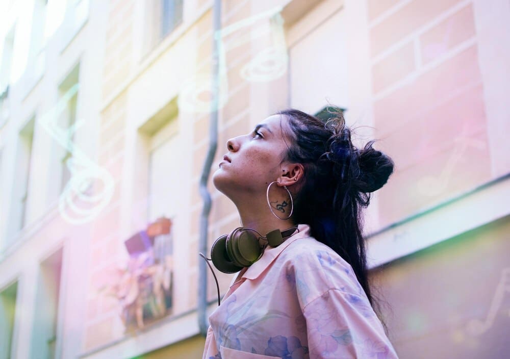 Woman stands in profile against a building.