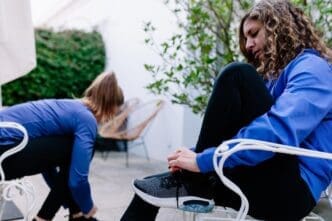 Woman sits on a chair and ties her shoelace.
