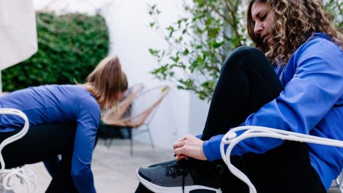 Woman sits on a chair and ties her shoelace.