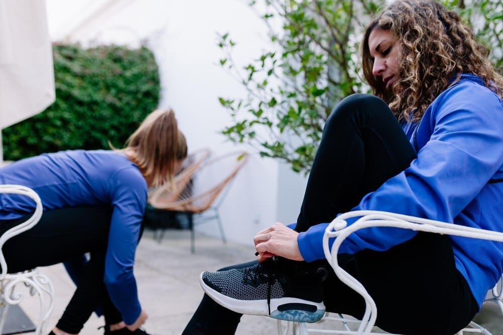 Woman sits on a chair and ties her shoelace.