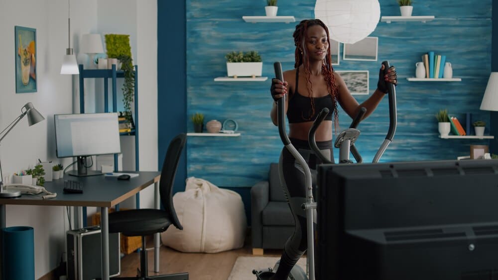 Woman in sportswear watches a fitness video on TV.