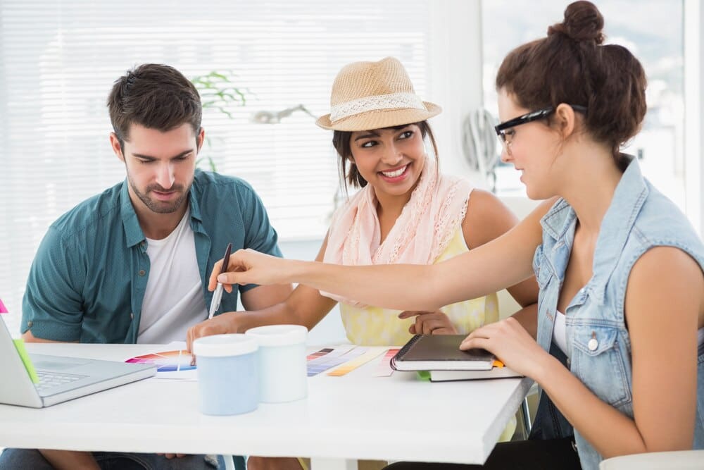 Smiling colleagues collaborate around a color wheel.