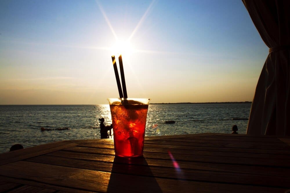 Sun setting over a calm sea, casting orange and pink hues across the water.