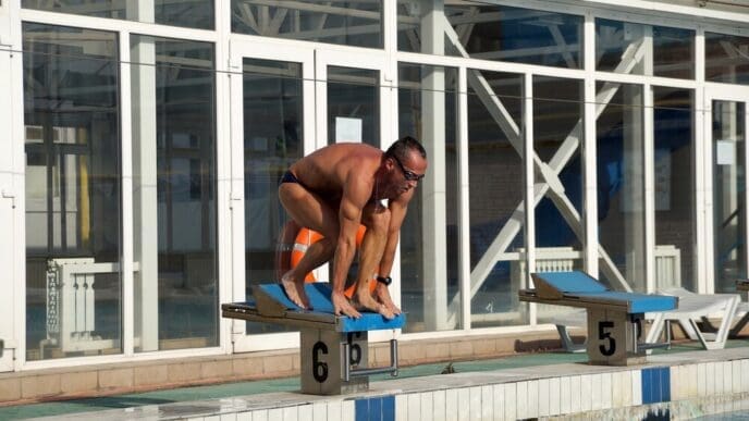 A swimmer is in a large outdoor swimming pool.