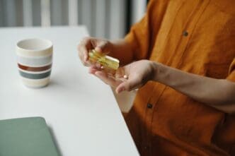 A person's hand reaches into a pill organizer to take a daily dose of medication.