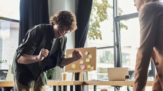 Team members cheer and high-five, celebrating a win during a game in a contemporary office.