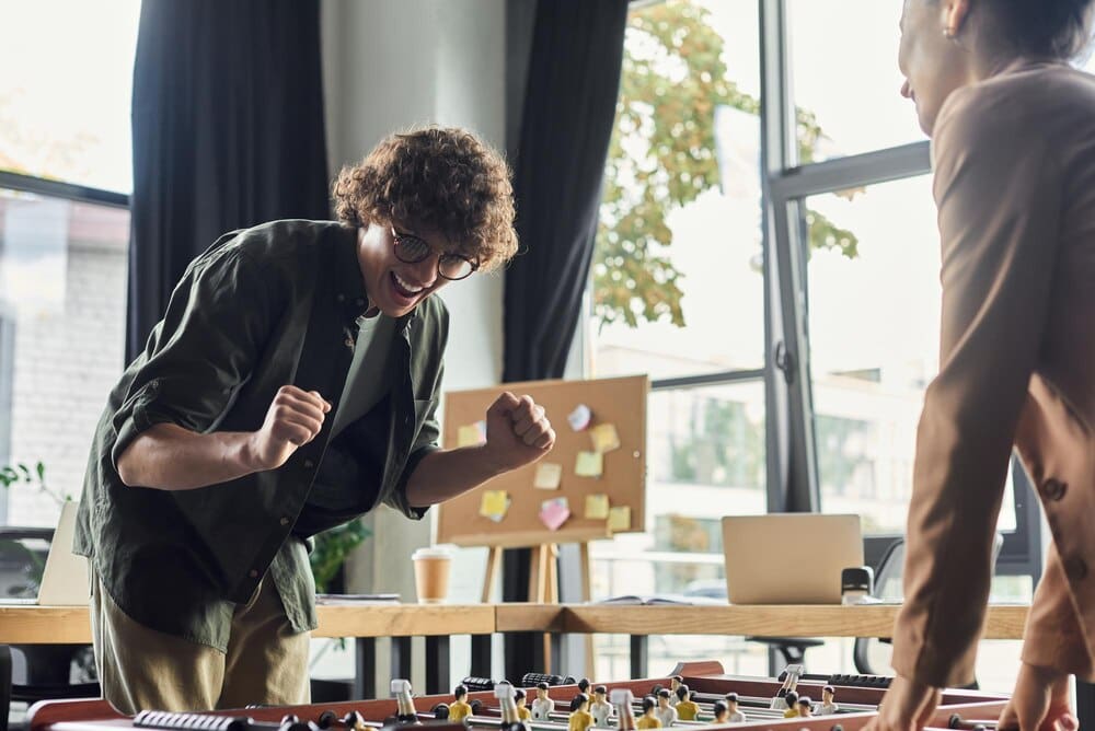 Team members cheer and high-five, celebrating a win during a game in a contemporary office.