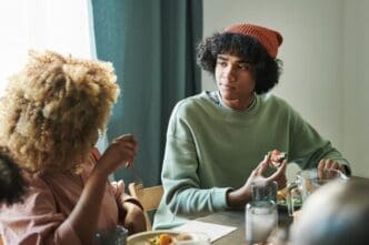 A teenage boy and his mother sit at a table, engaged in conversation during a home dinner.