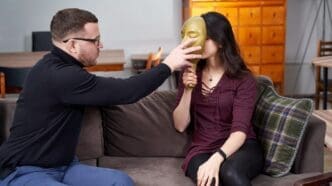 Therapist places a clear plastic mask on a patient's face during a therapy session.