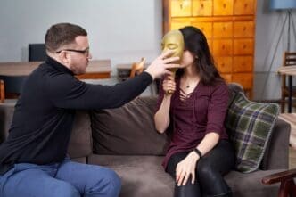 Therapist places a clear plastic mask on a patient's face during a therapy session.