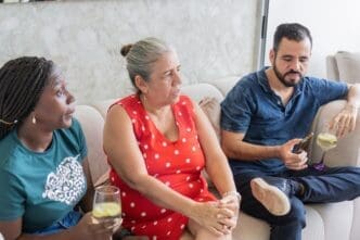 Three people seated on a couch are engaged in a conversation.