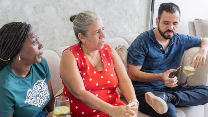 Three people seated on a couch are engaged in a conversation.