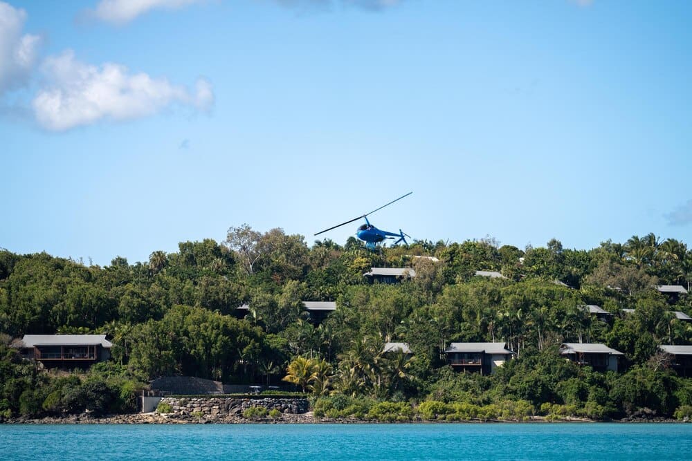 Aerial view of lush, tropical islands and luxurious super yachts dotting the turquoise waters off the coast of Queensland, Australia.