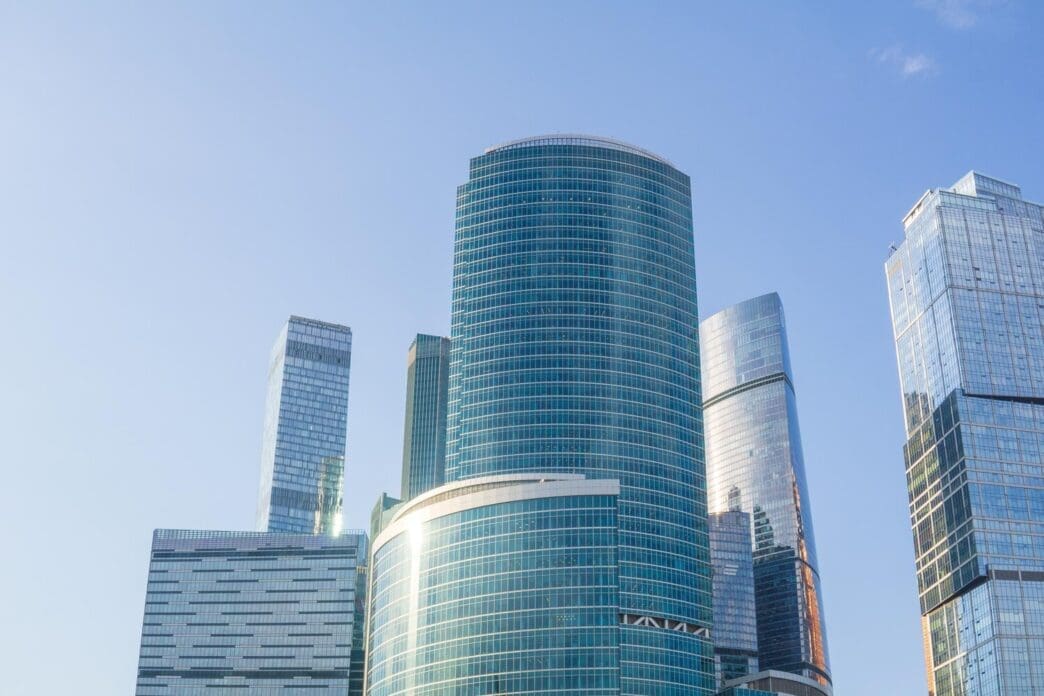 Skyscrapers tower over a modern business center against a bright blue sky.
