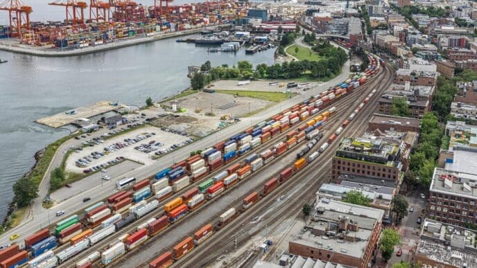A wide view of the Vancouver Port shows a container port terminal and freight station with trains and tank cars.