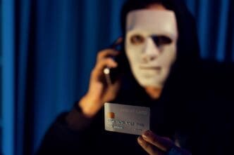 White criminal mask with a sinister expression, overlaid with text about a credit card ransom.